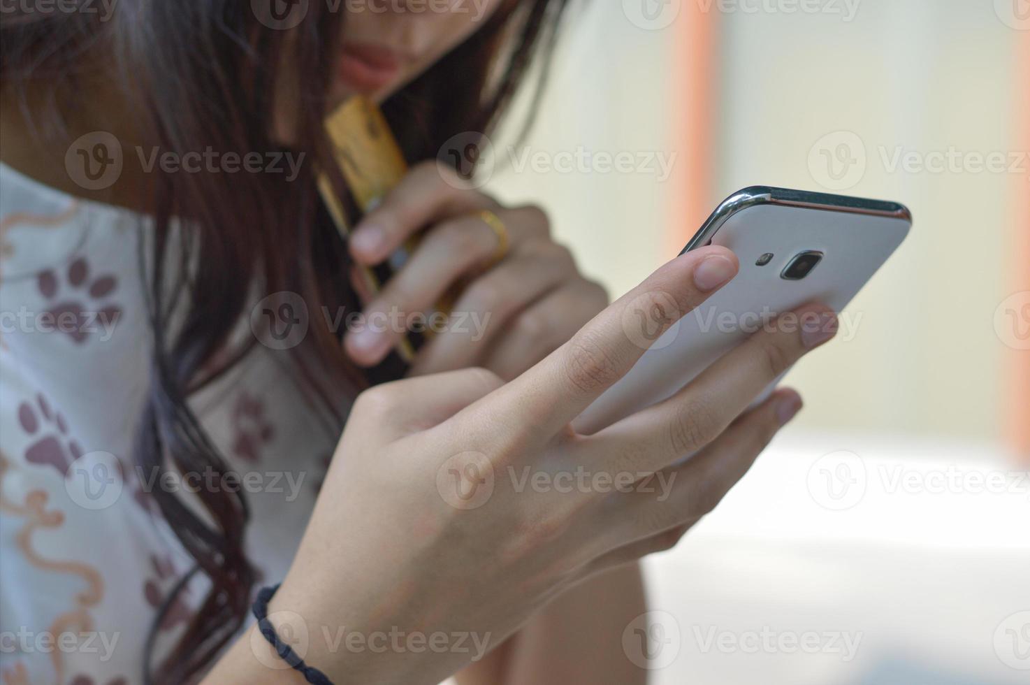 vrouw die smartphone gebruikt om online met creditcard te kopen foto