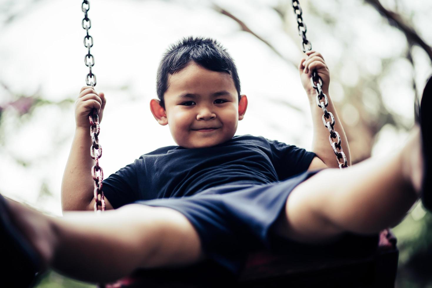 schattige kleine jongen met plezier op een schommel buitenshuis foto