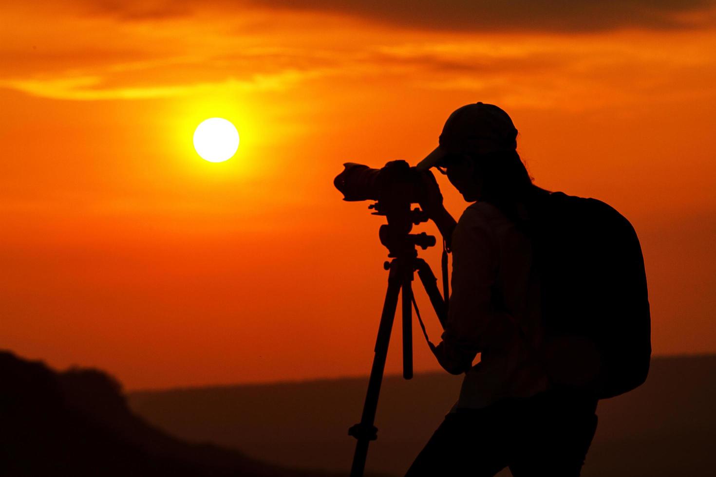 silhouet van Aziatische persoon die een foto in de zonsondergang