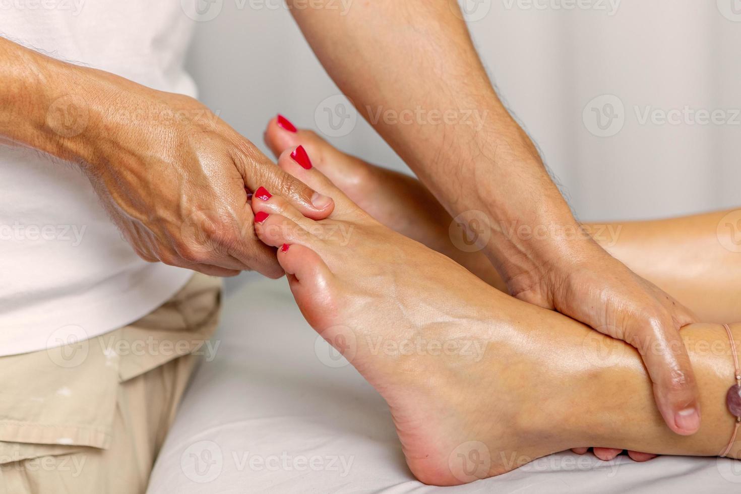 dichtbij omhoog visie van handen van masseur geven een olie voet massage in spa centrum foto