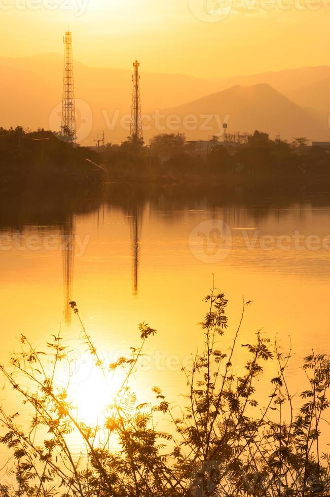 zonsondergang Aan de meer in nevelig met elektriciteit lijnen in achtergrond foto