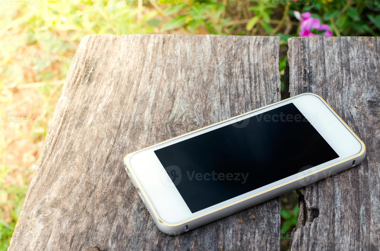 smartphone Aan oud bruin hout achtergrond in de tuin foto