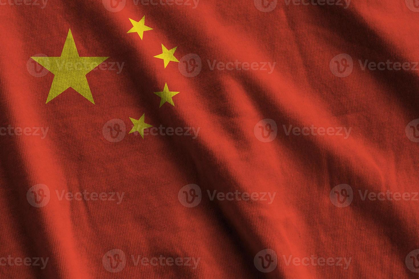 China vlag met groot vouwen golvend dichtbij omhoog onder de studio licht binnenshuis. de officieel symbolen en kleuren in banier foto