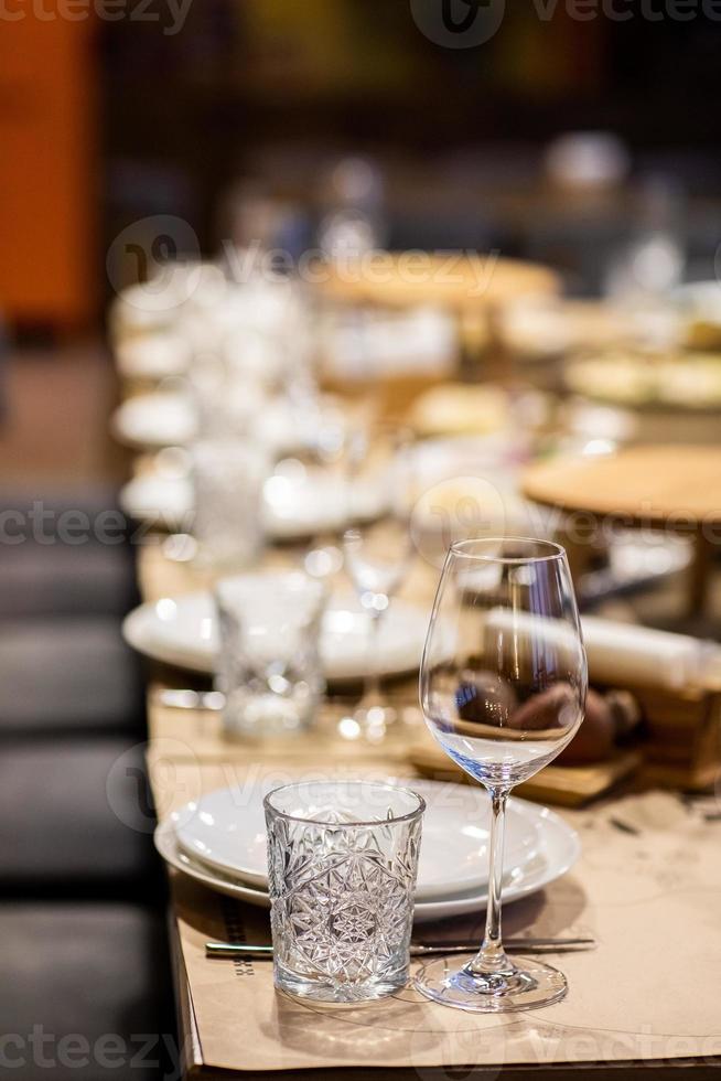 leeg glas reeks in restaurant. bruiloft, decor, viering, vakantie concept - romantisch tafel instelling met wit tafelkleed, platen, kristal bril foto