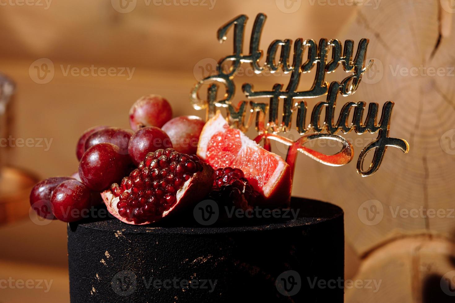 grote zwarte verjaardagstaart met vers fruit en snoep op een feestelijke tafel. snoepreep. tafel met verschillende snoepjes voor feest foto