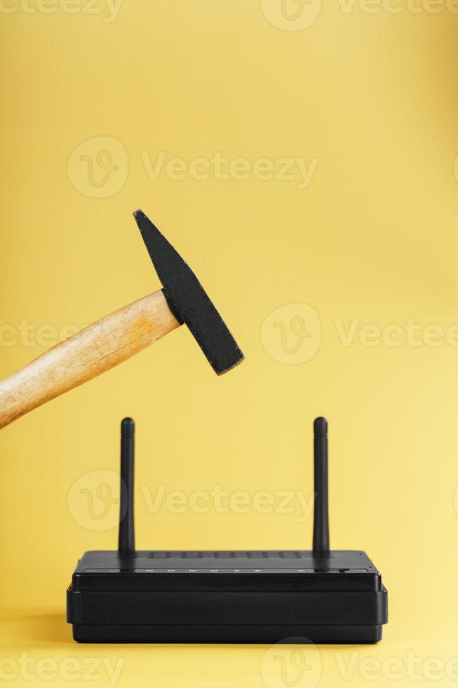 hamer over- de Wifi router voor verwoesting Aan een geel achtergrond. foto