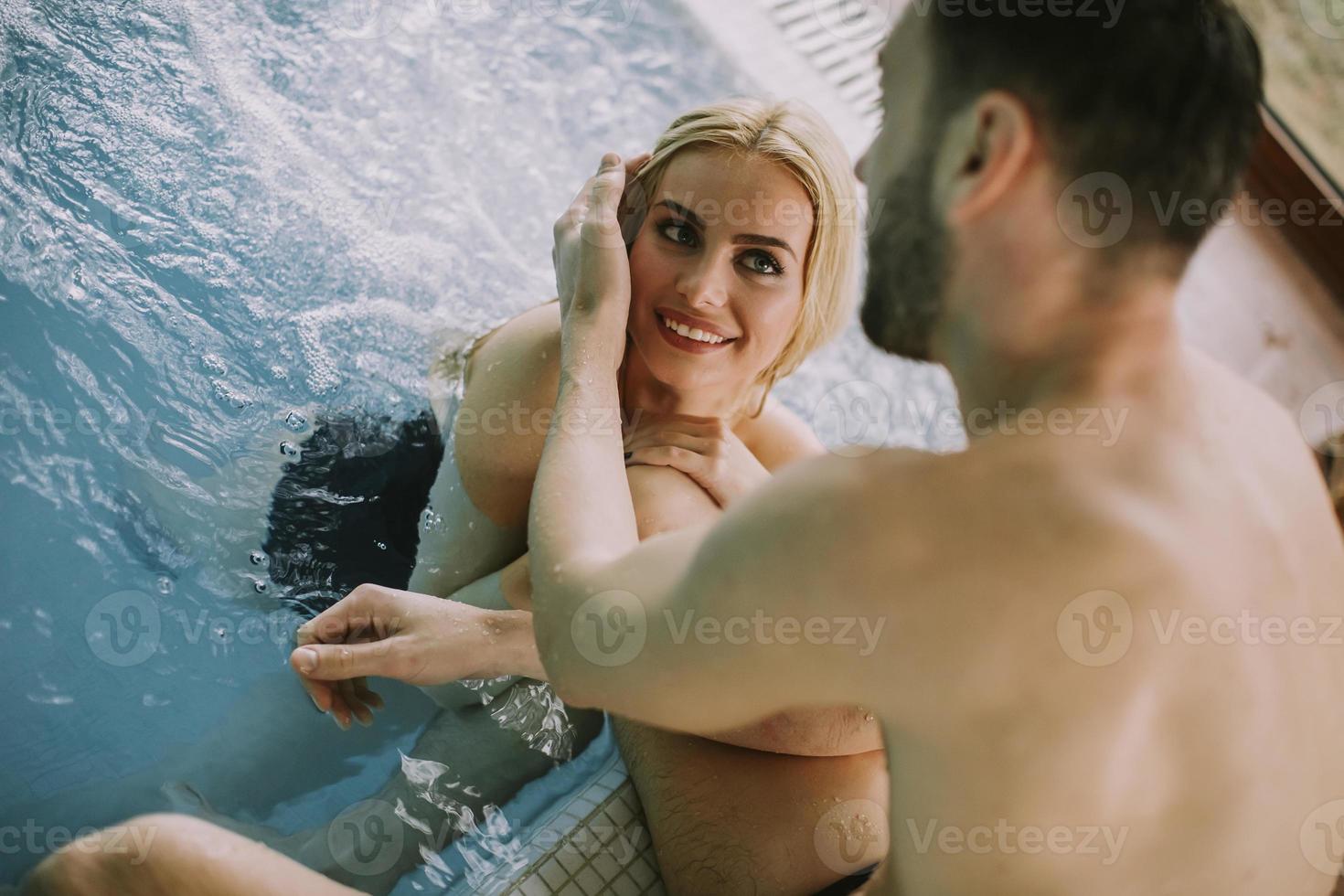 jong koppel ontspannen aan het zwembad van het interieur zwembad foto