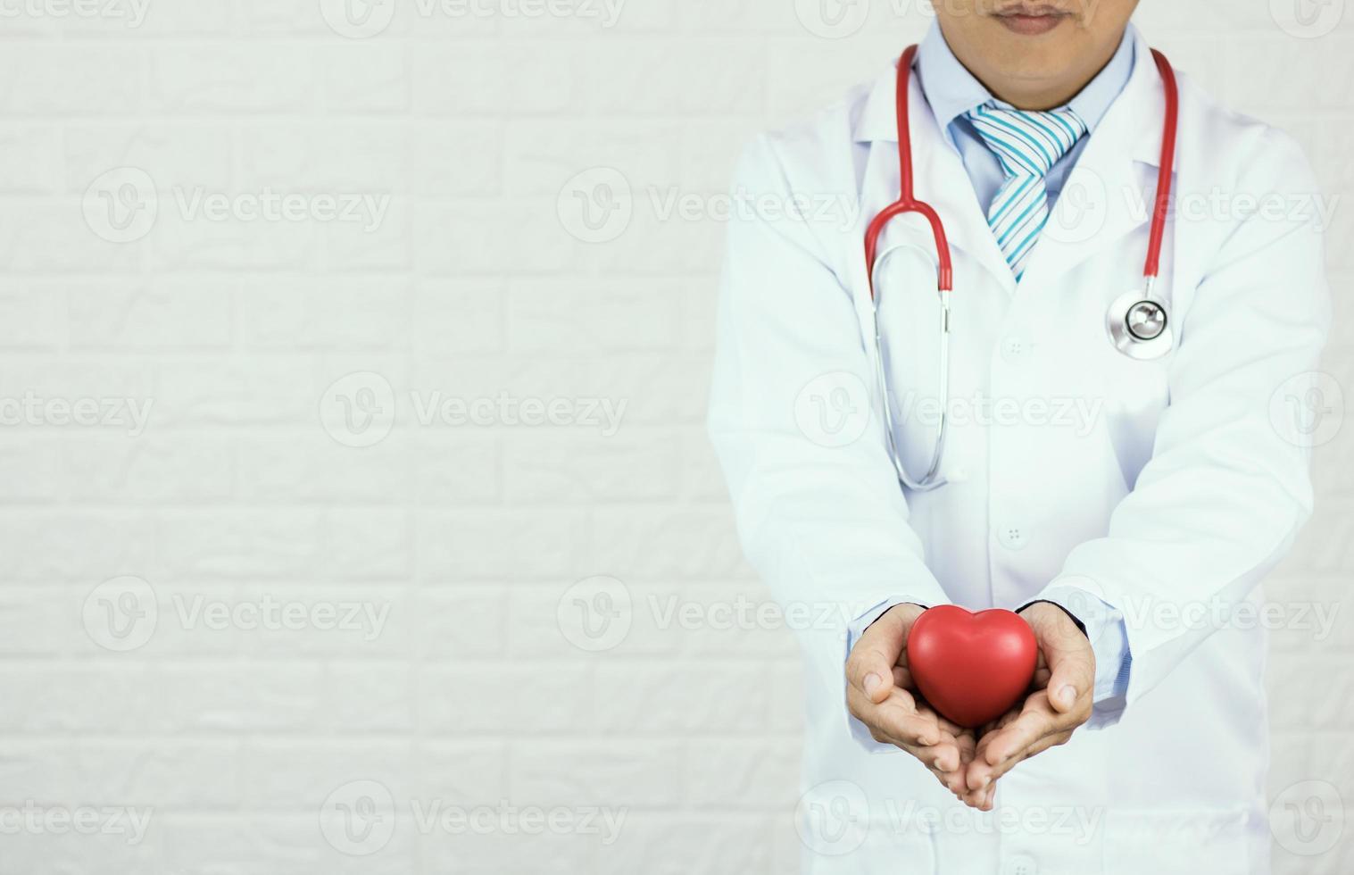 arts die rood hart op witte bakstenen muurachtergrond houdt foto