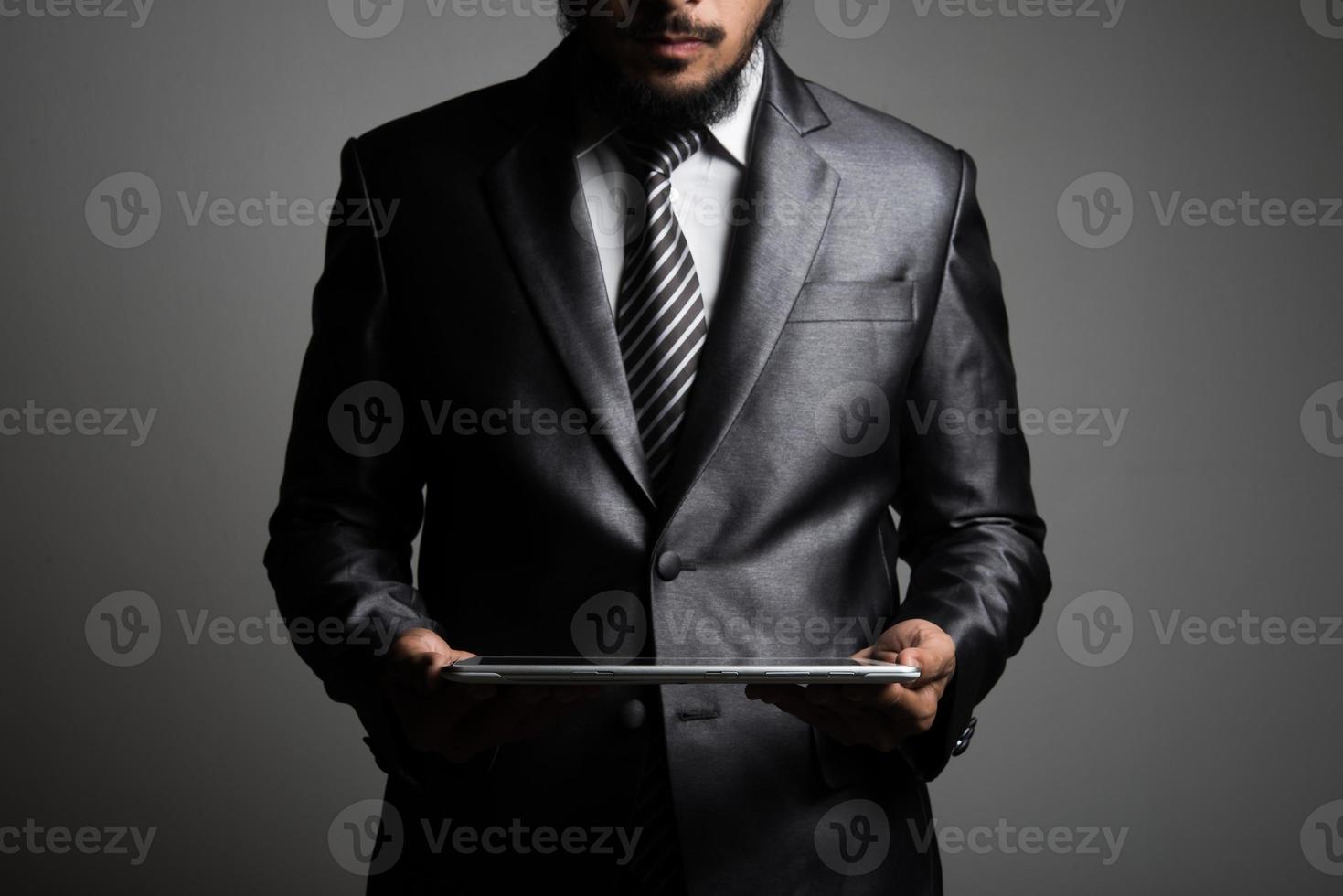 knappe zakenman kijken naar een tablet, geïsoleerd op zwarte achtergrond foto