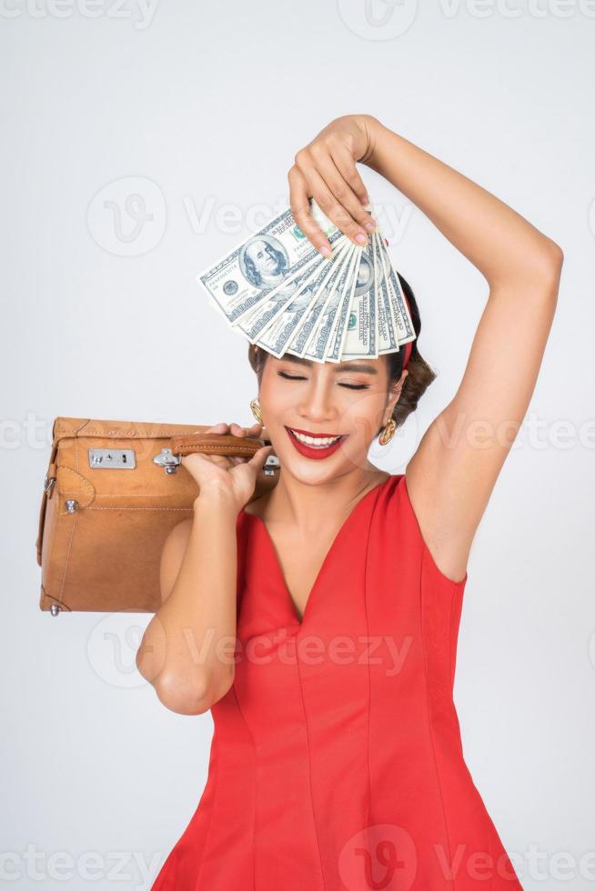 retro modieuze vrouw houdt bagage en geld om te reizen foto