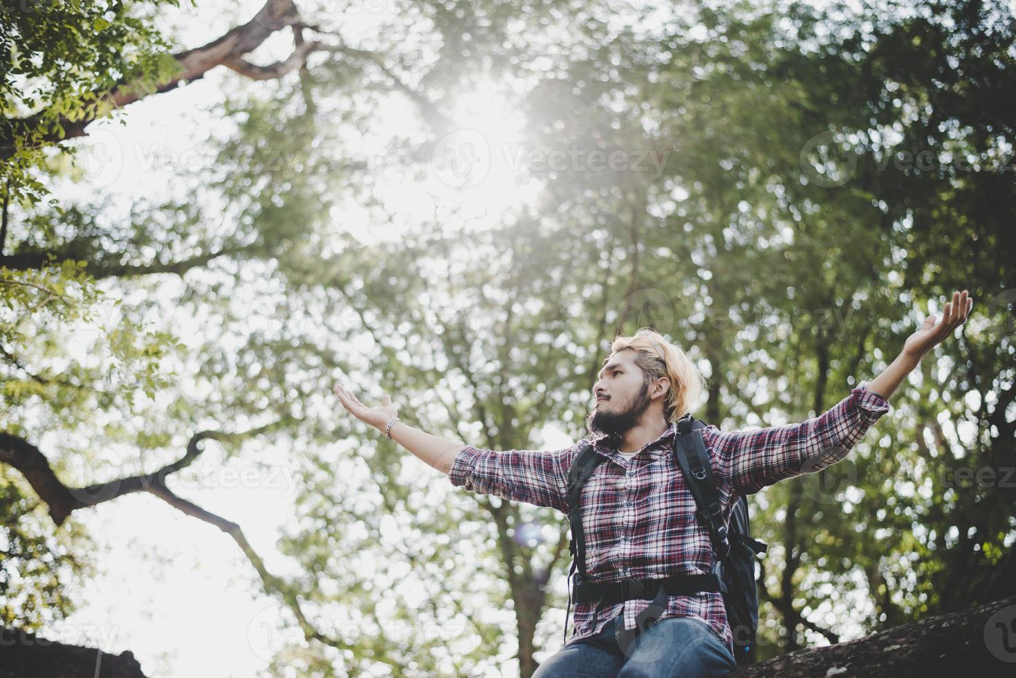 jonge hipster man zittend op een boomtak in het park. foto