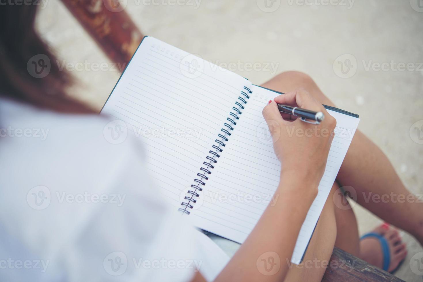 mooie jonge vrouw op een schommel die op haar blocnote schrijft foto