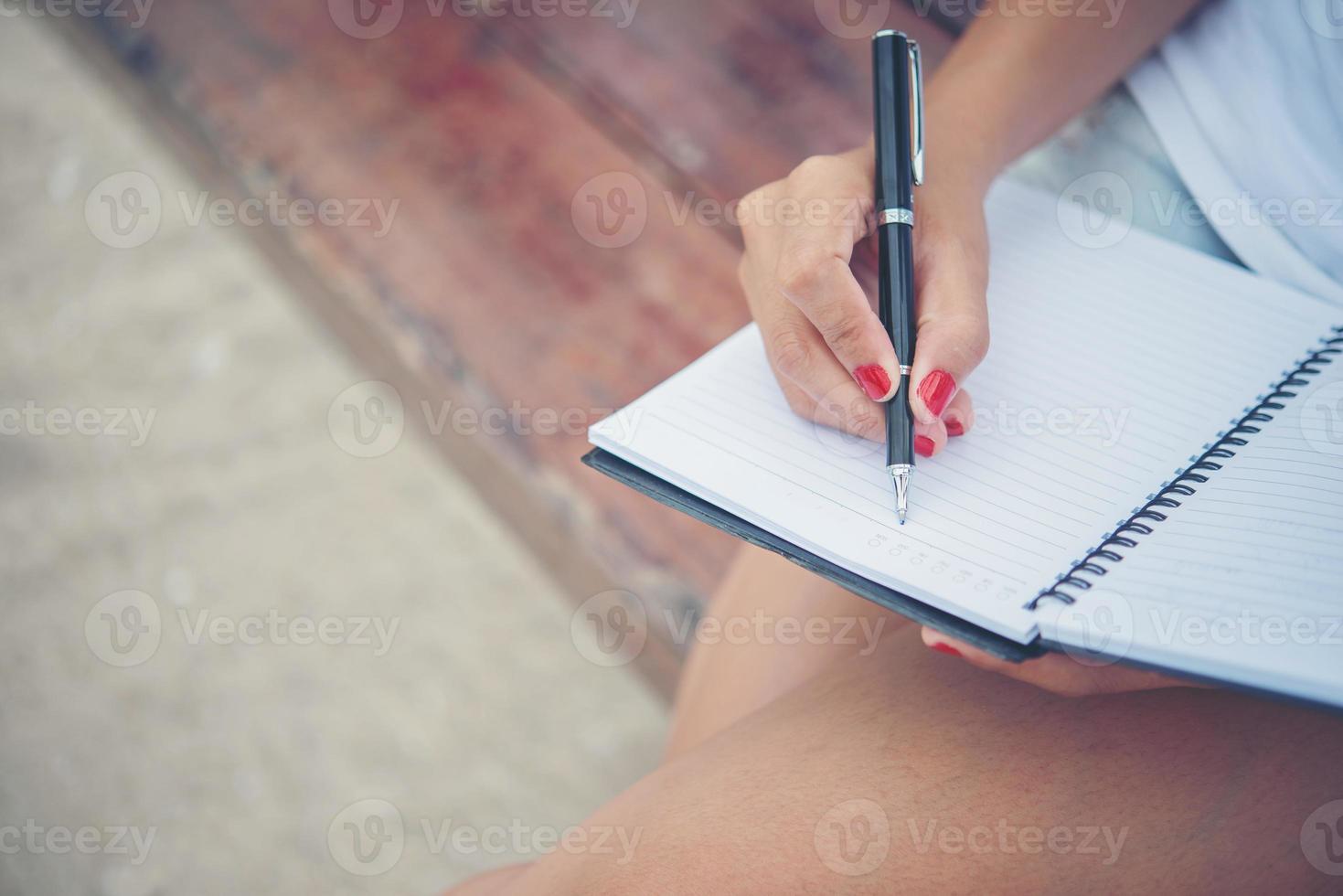 mooie jonge vrouw op een schommel die op haar blocnote schrijft foto