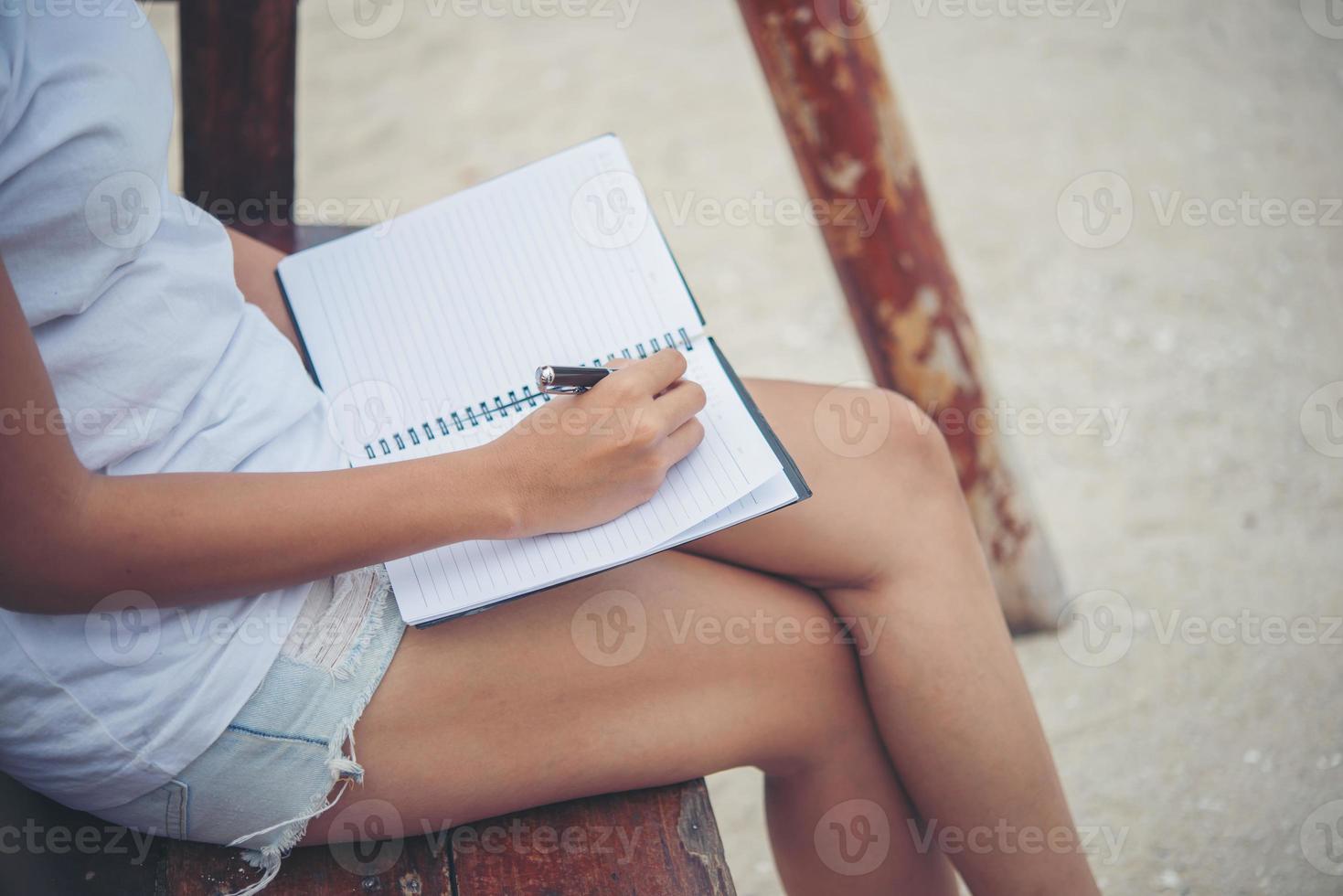 mooie jonge vrouw op een schommel die op haar blocnote schrijft foto