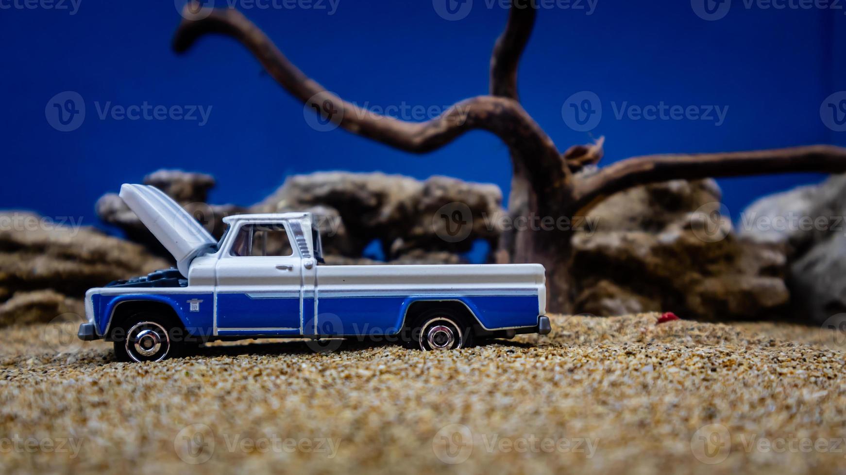 minahasa, Indonesië januari 2023, een speelgoed- auto Aan de zand met een achtergrond van rotsen en blauw lucht foto