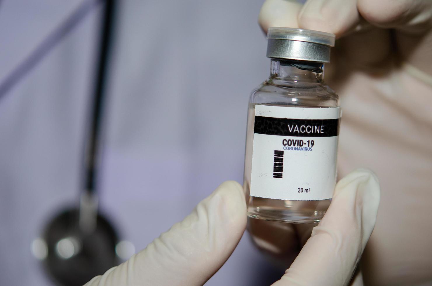 een mannelijke arts die een fles covid-19 of het coronavirusvaccin vasthoudt foto
