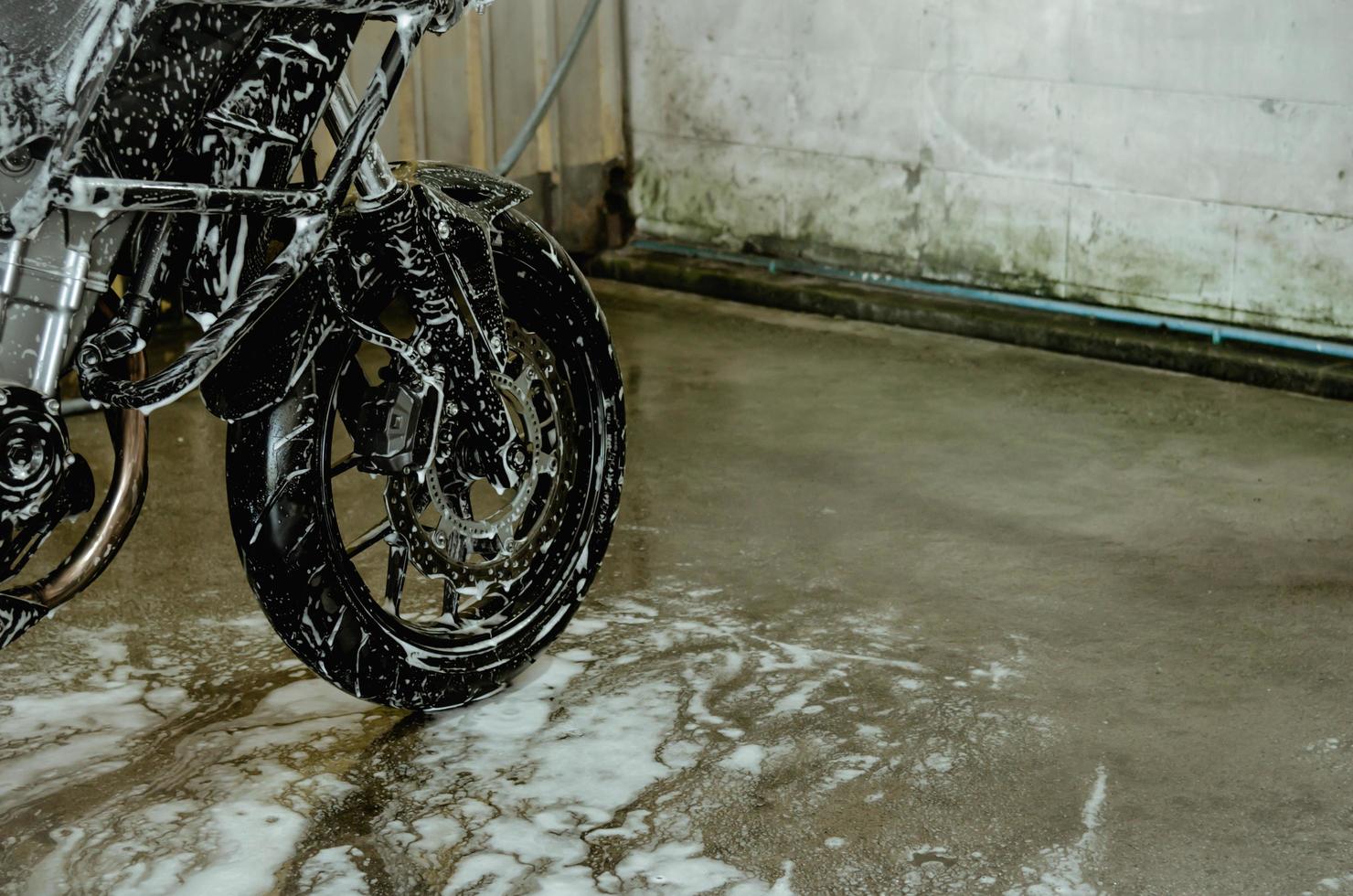 een motorfiets wassen in de autowaswinkel. schuim autowasstraat op wielen foto