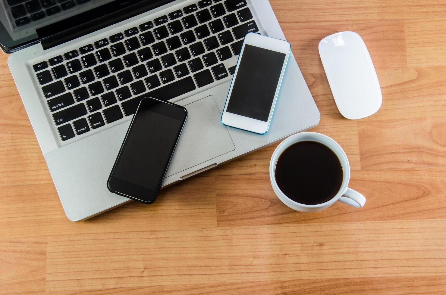 een laptop en smartphones op een oud houten bureau foto