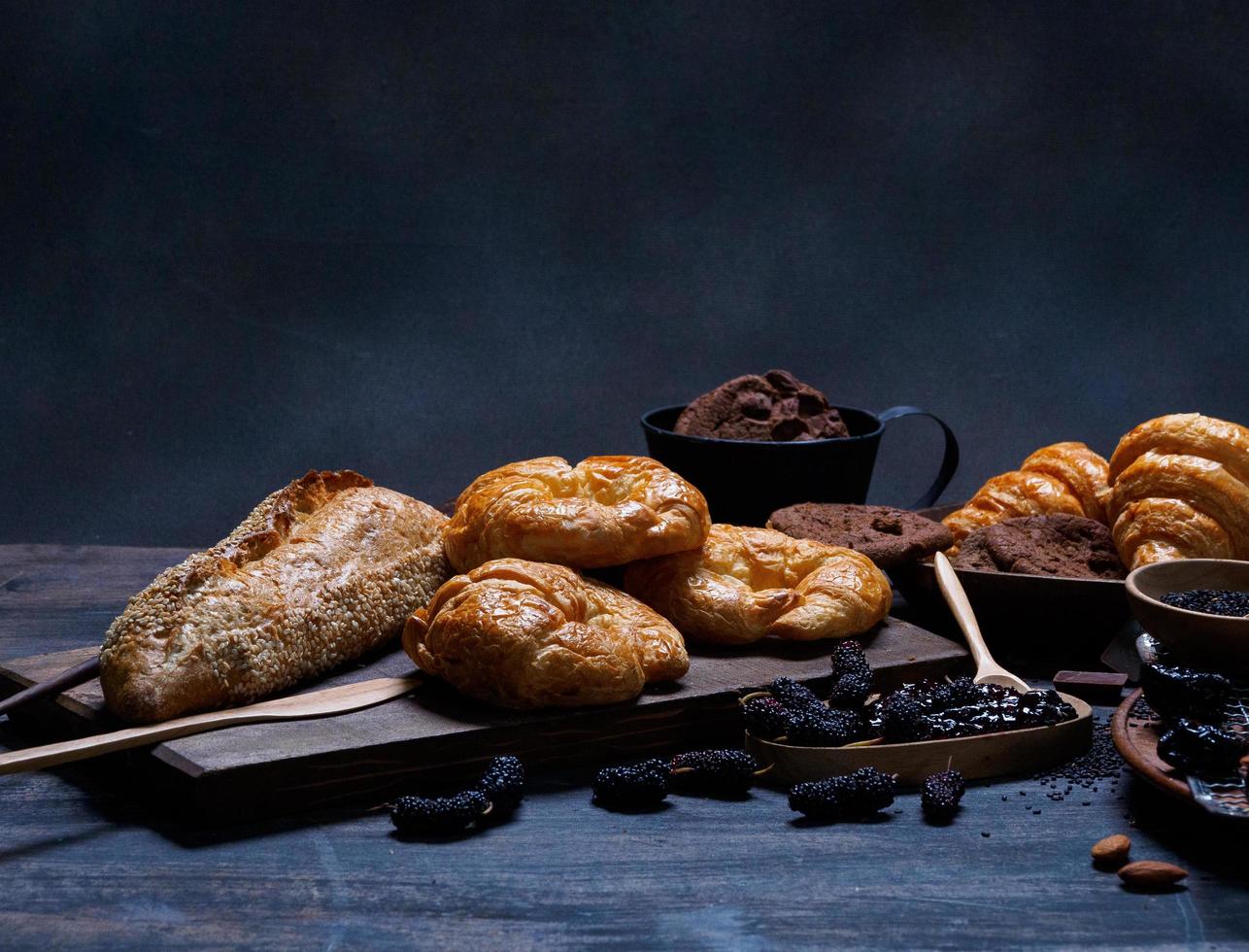 bovenaanzicht vers brood bruin rozijnen sesam bakkerij gemaakt van tarwemeel voedsel zelfgemaakte geschikt voor gezond eten op houten tafelvloer zwarte rustieke donkere achtergrond foto