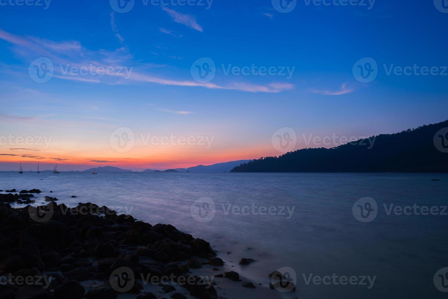 kleurrijke zonsondergang over de oceaan met bergen foto