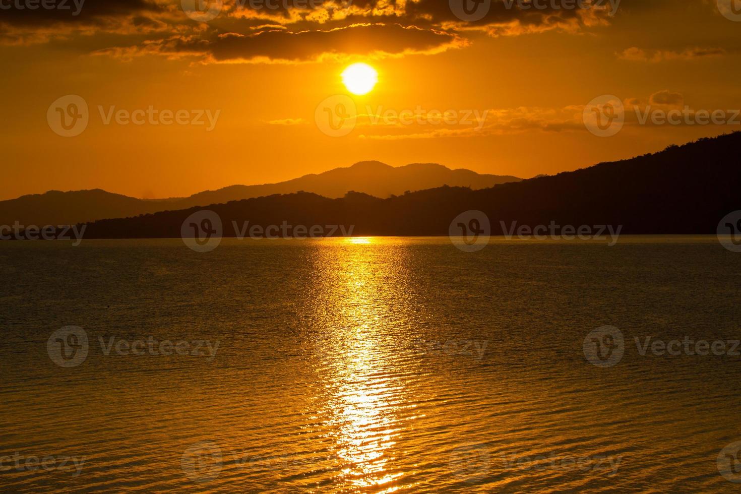 oranje zonsondergang over de oceaan en de bergen foto
