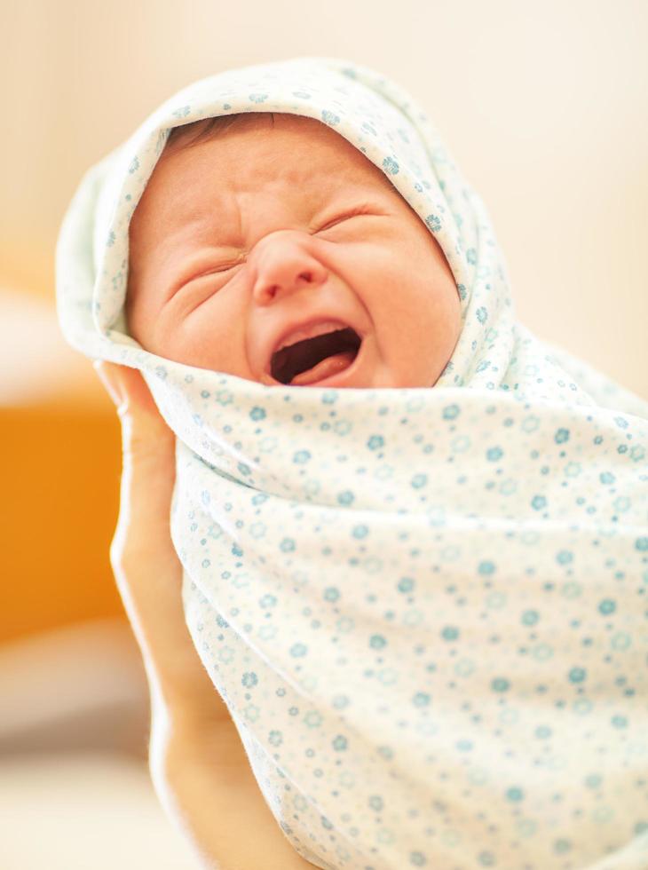 huilende pasgeborene in moeders handen foto