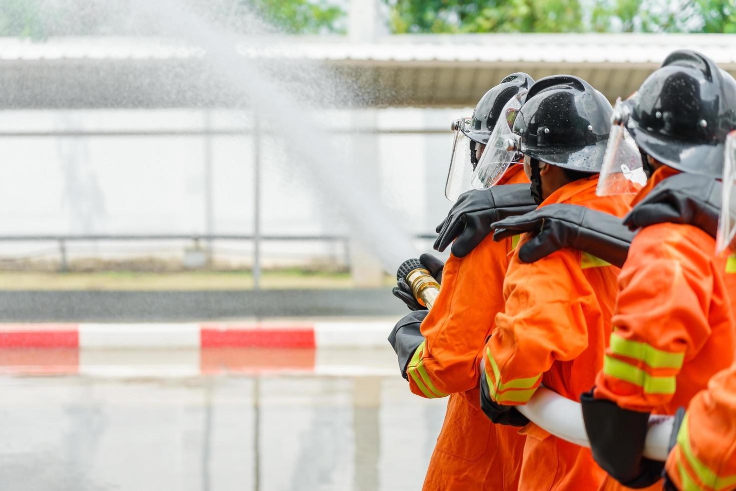 brandweerlieden die een brandblusser en water uit een slang gebruiken foto