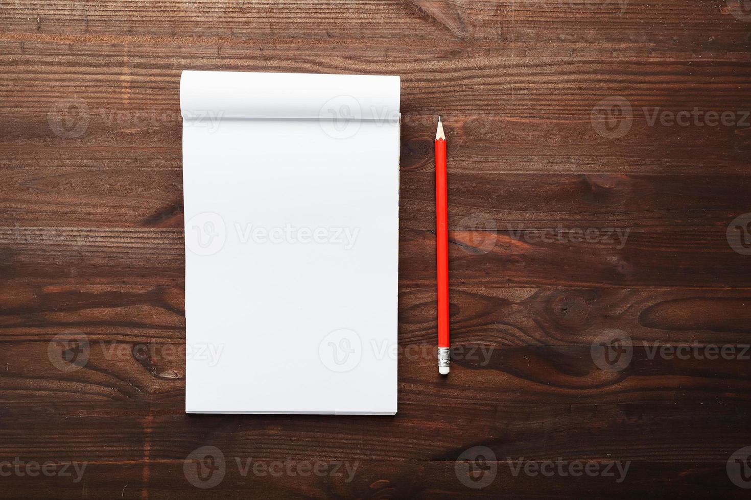 kladblok met rood potlood Aan een bruin houten tafel achtergrond, voor opleiding, schrijven doelen en daden foto