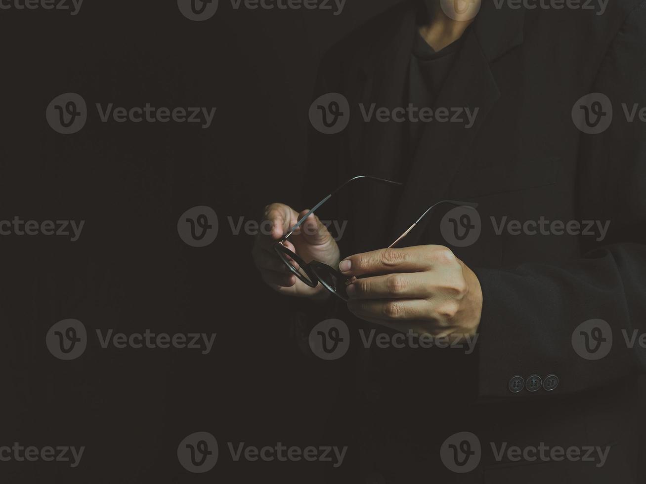 zakenman Holding bril in hand- Aan een zwart achtergrond foto