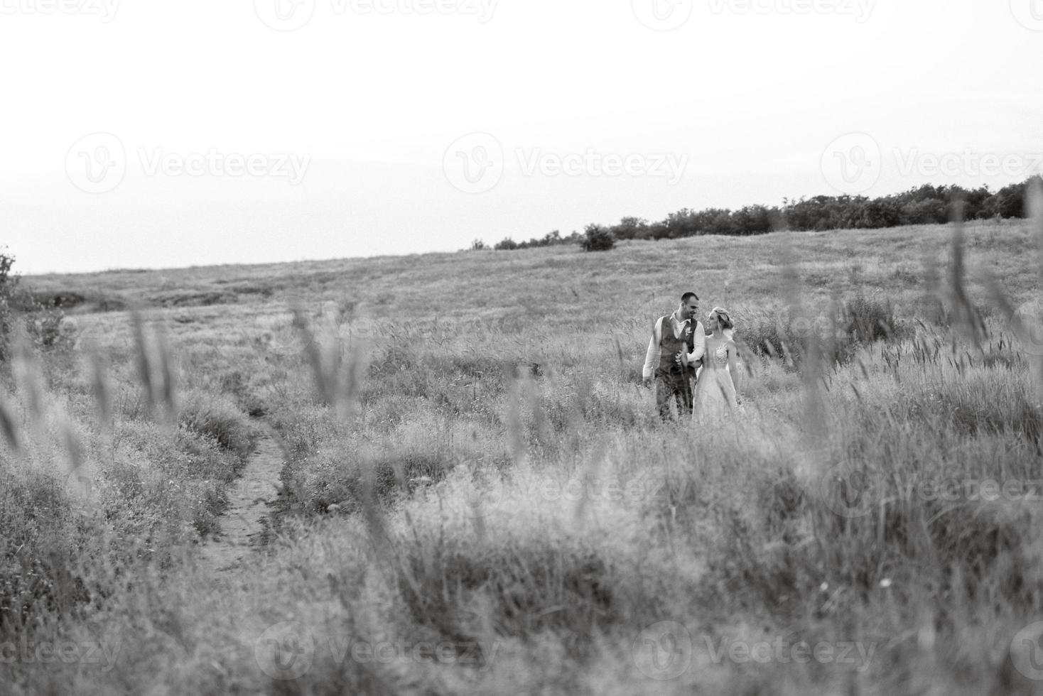 bruid blond meisje en bruidegom in een veld- foto