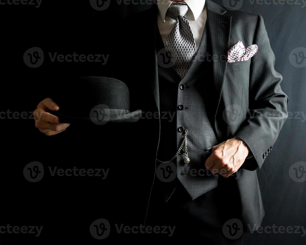 portret van heer in donker sui Holding bowler hoed. wijnoogst stijl en retro mode van klassiek Engels heer. foto