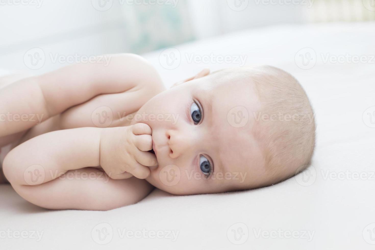 babymeisje liggend met hand in de mond foto