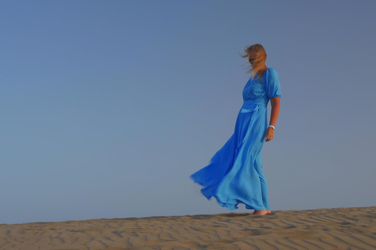 vrouw op een zandduin in een blauwe jurk foto