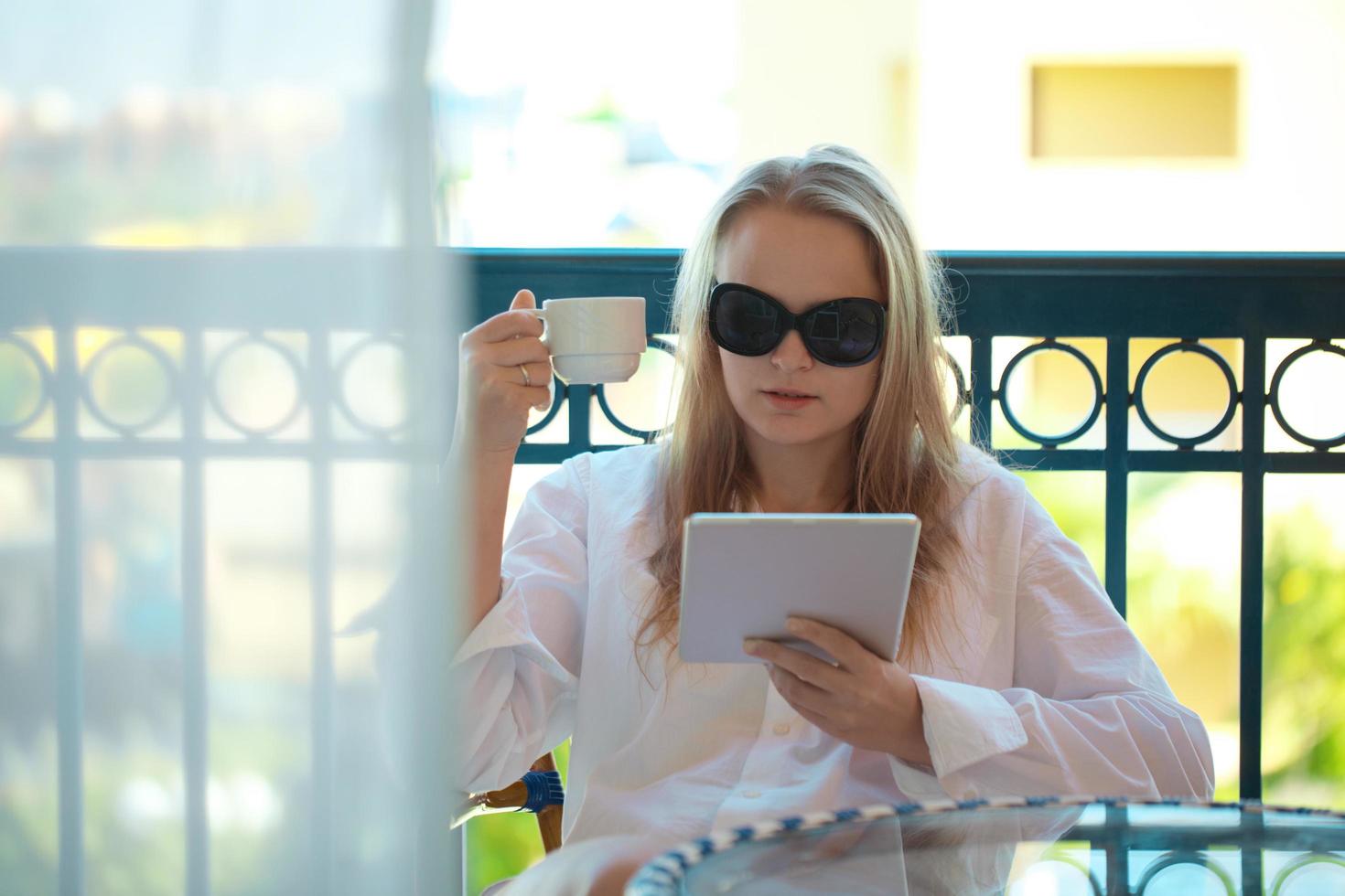 vrouw met behulp van een tablet en een kopje koffie te houden foto