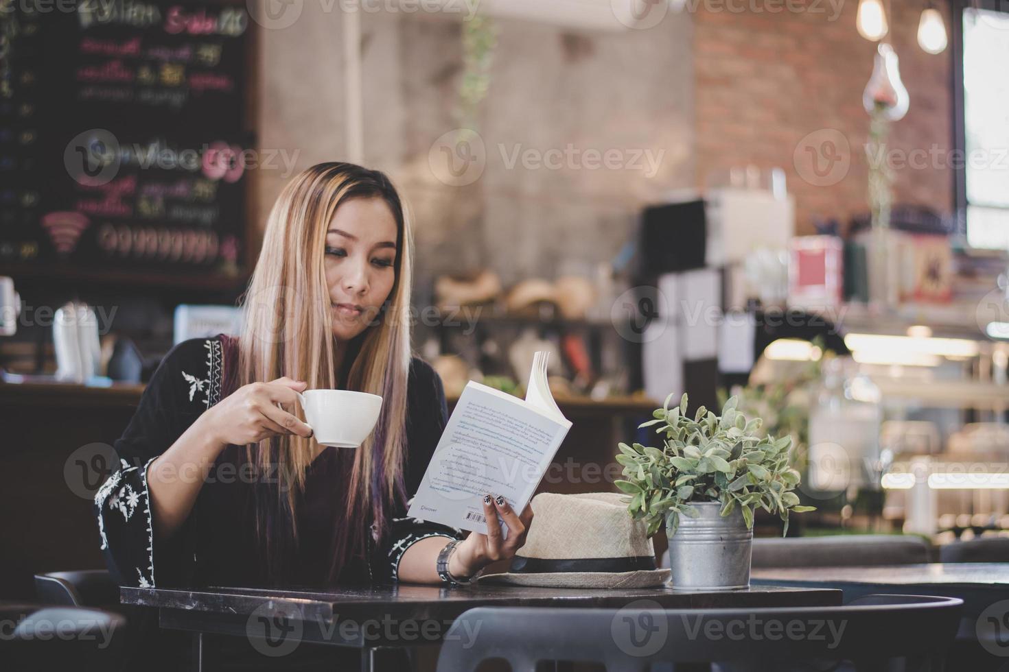 gelukkig zakenvrouw leesboek terwijl u ontspant in café foto