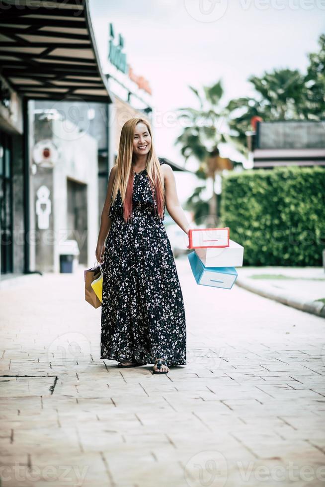 portret van een jonge vrouw gelukkig met boodschappentassen wandelen in de straat foto
