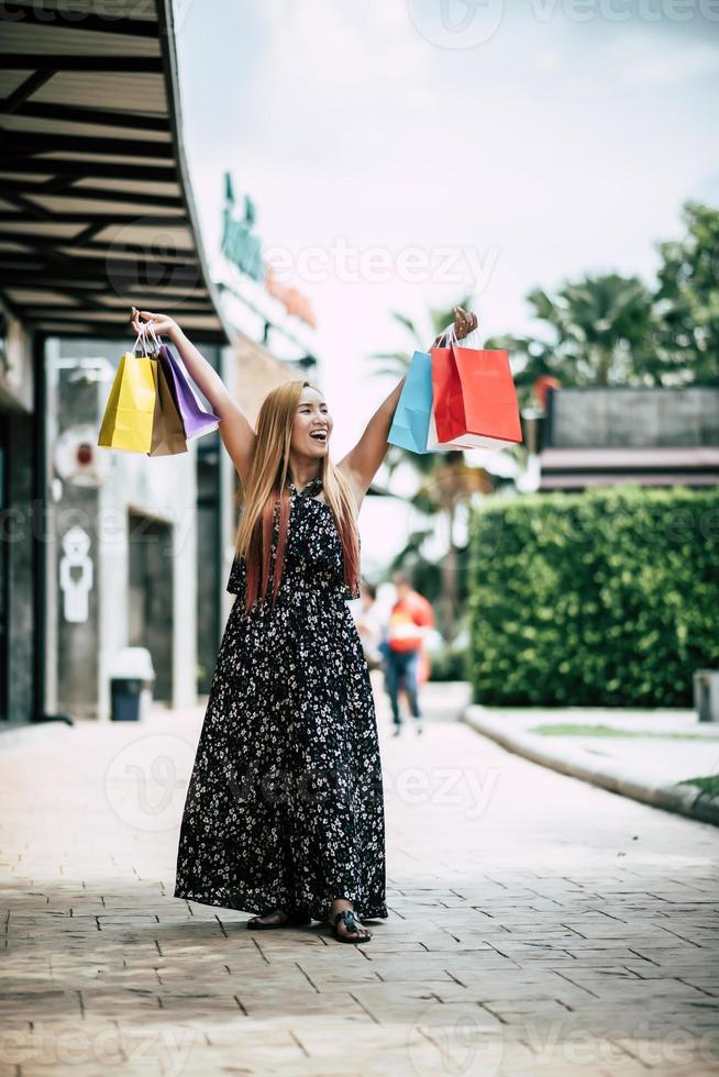 portret van een jonge vrouw gelukkig met boodschappentassen wandelen in de straat foto