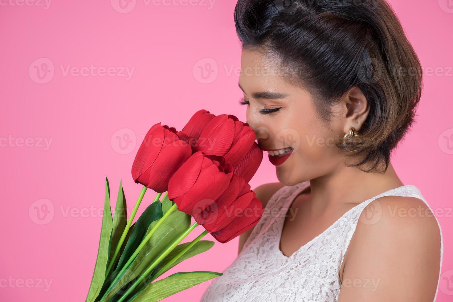 portret van een mooie vrouw met een boeket van rode tulp bloemen foto