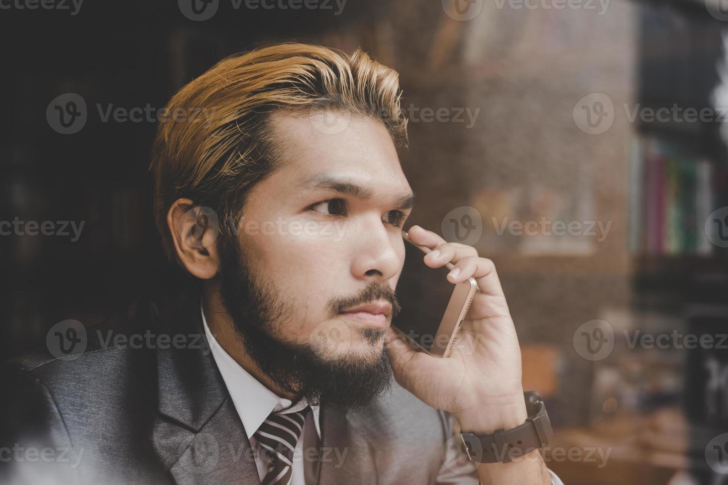 jonge knappe zakenman bedrijf praten met zijn telefoon zittend aan café-bar foto