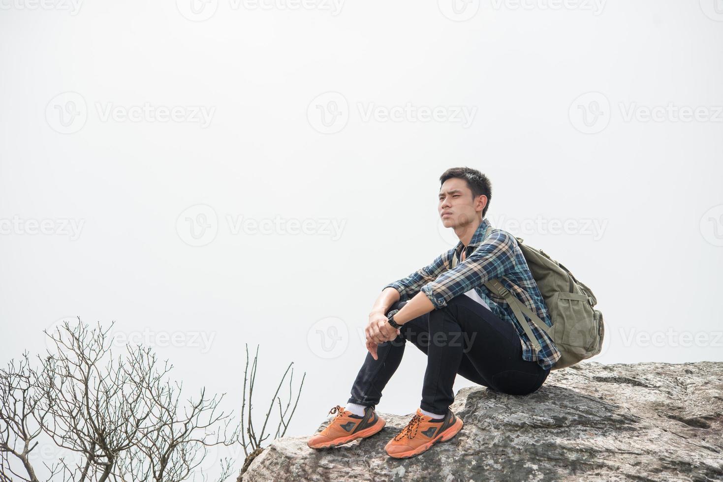 jonge hipster wandelaar met rugzak zittend op de top van de berg foto