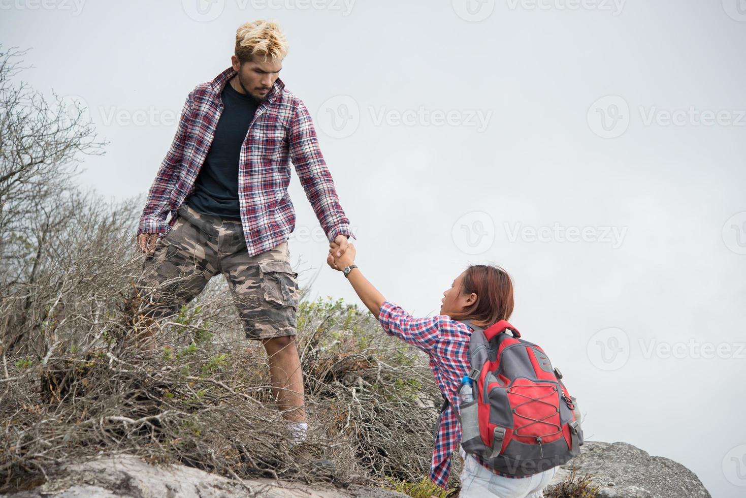 jonge hipster man helpen vrouw berg beklimmen foto