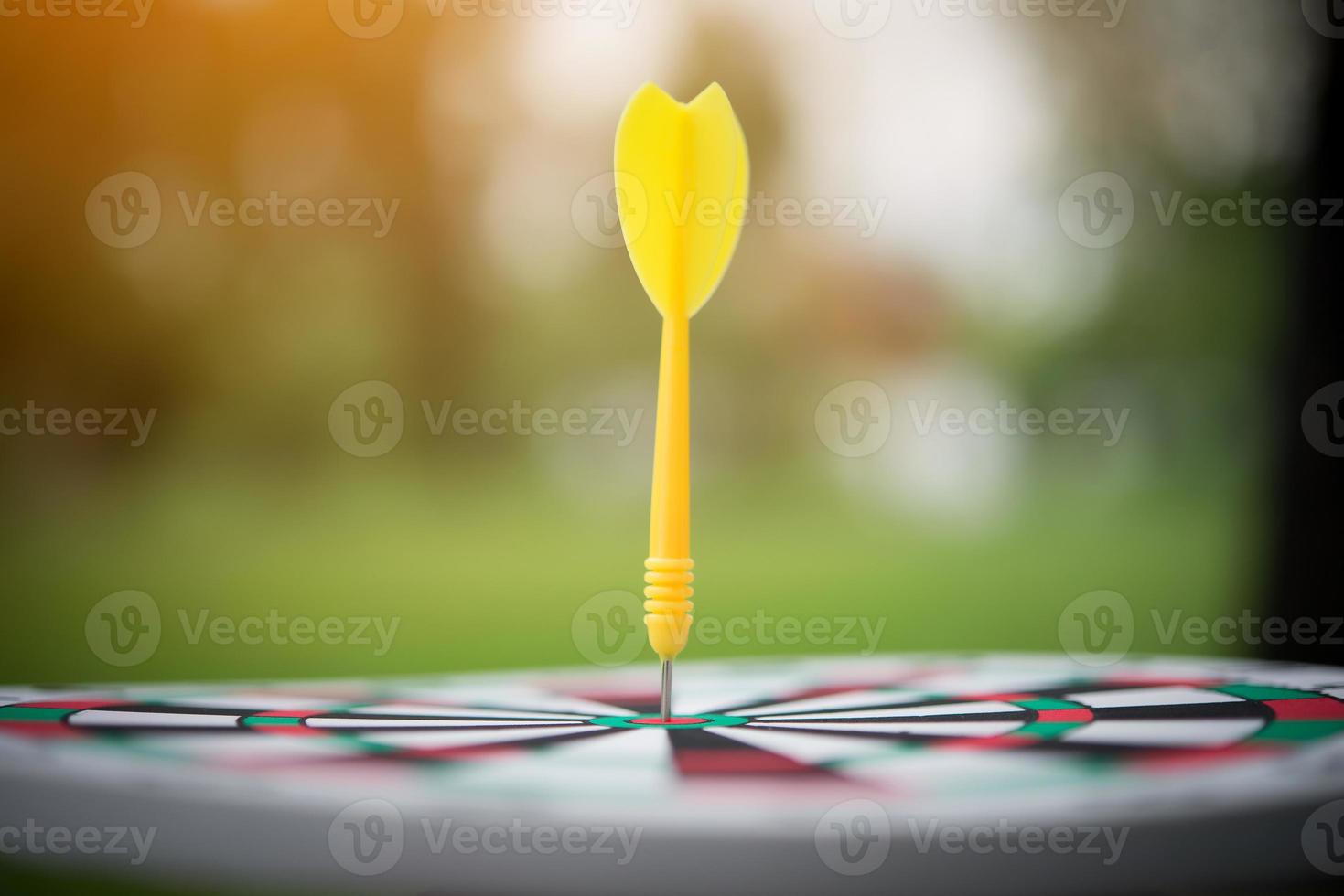 gele dartpijl in het midden van het dartbord foto