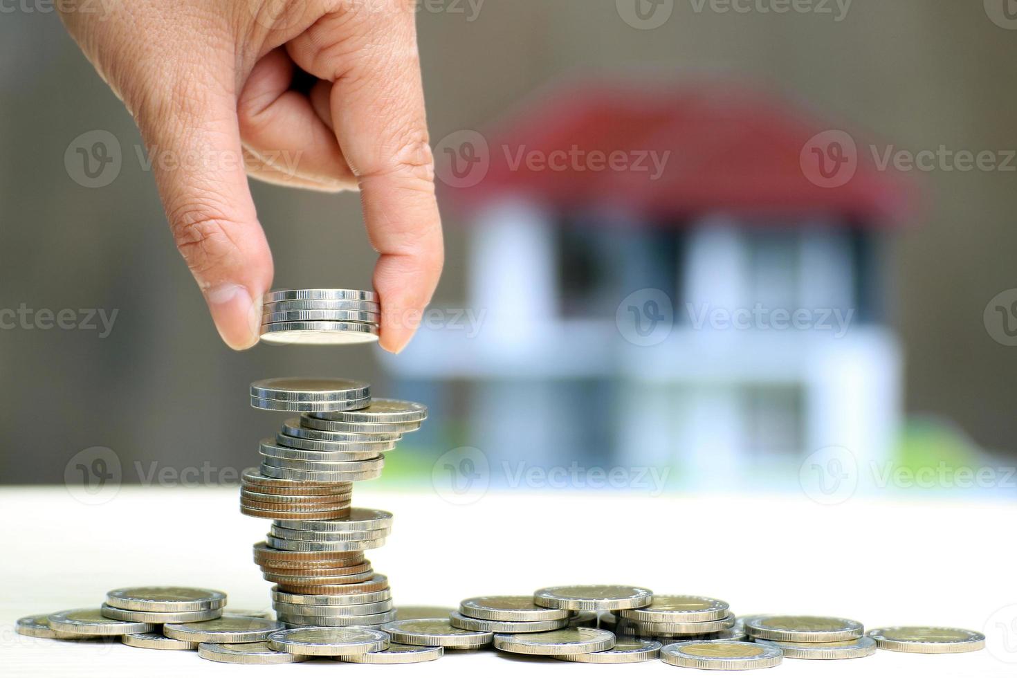 hand stapelen munten met onscherp huis op achtergrond foto