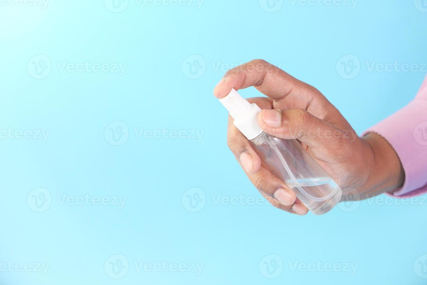 close-up van jonge man hand met hand sanitizer spray foto