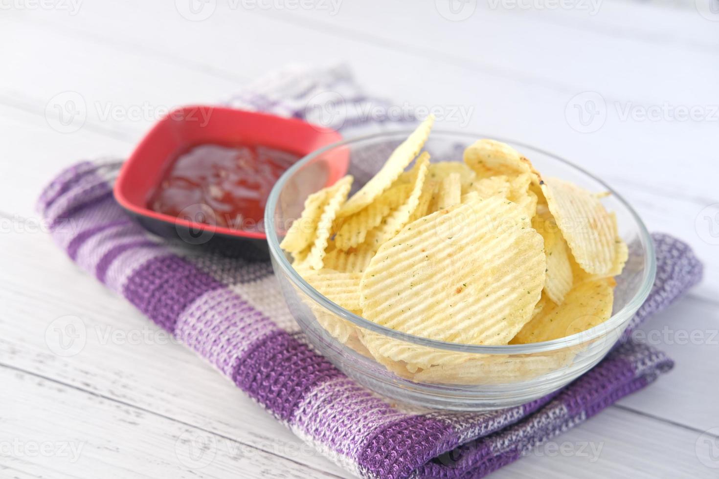 kom met smakelijke chips op houten achtergrond foto