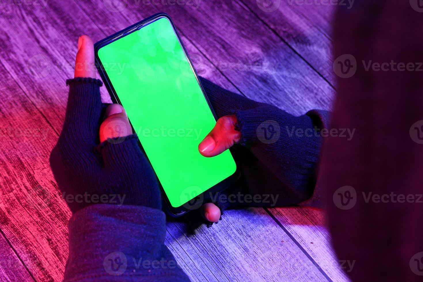 hacker's hand steelt gegevens van smartphone in neon donker licht foto