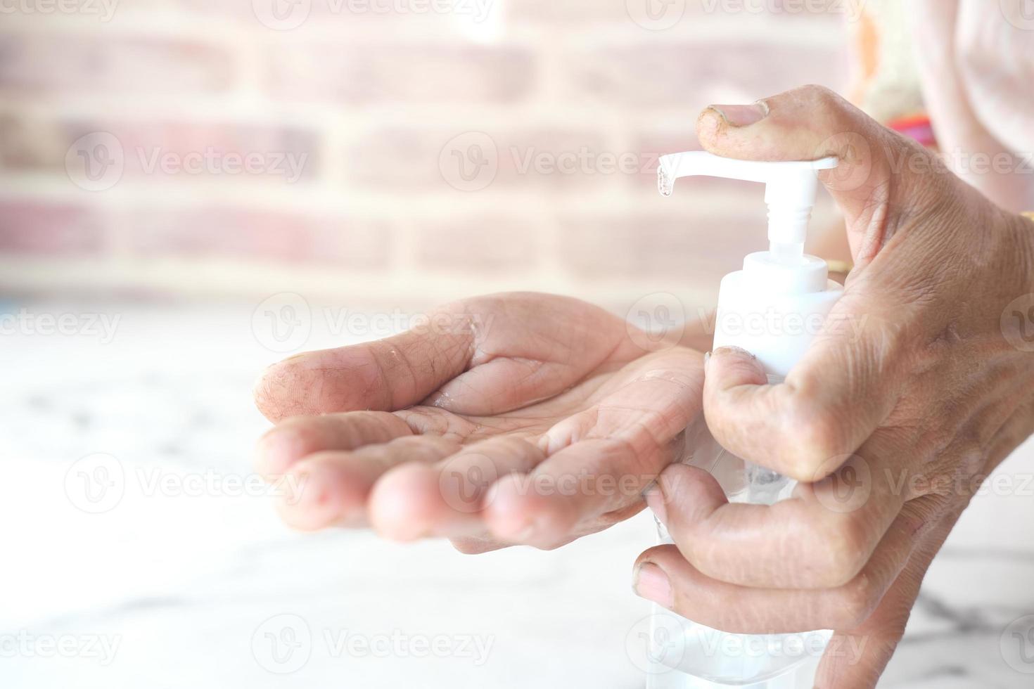 close-up van senior vrouw met behulp van handdesinfecterende gel om virussen te voorkomen foto