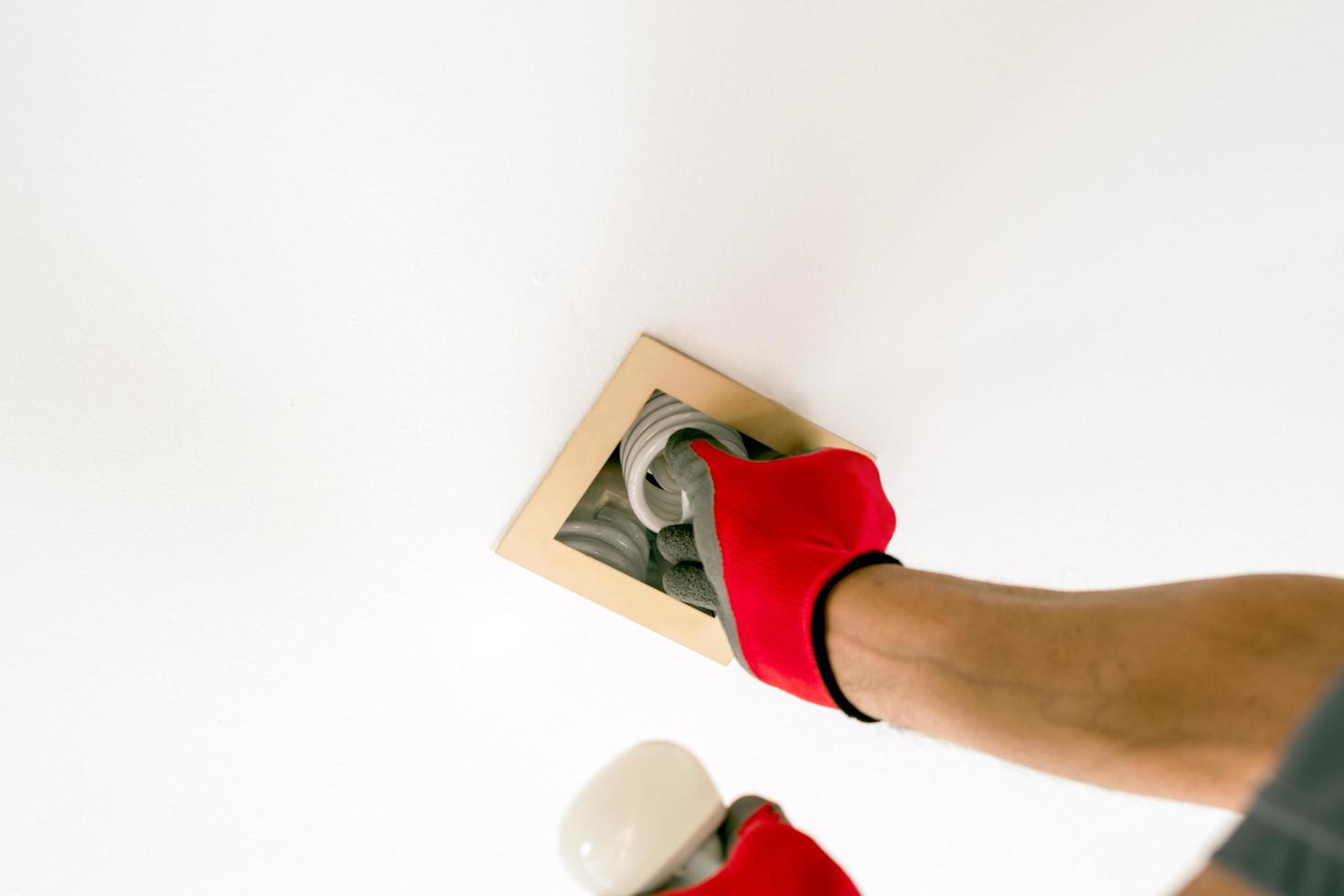 twee handen in handschoenen die een tl-lamp vervangen door een led-lamp foto