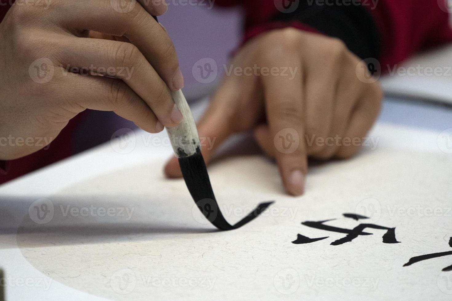 Japans vrouw schrijven naam Charles in ideogrammen met borstel foto