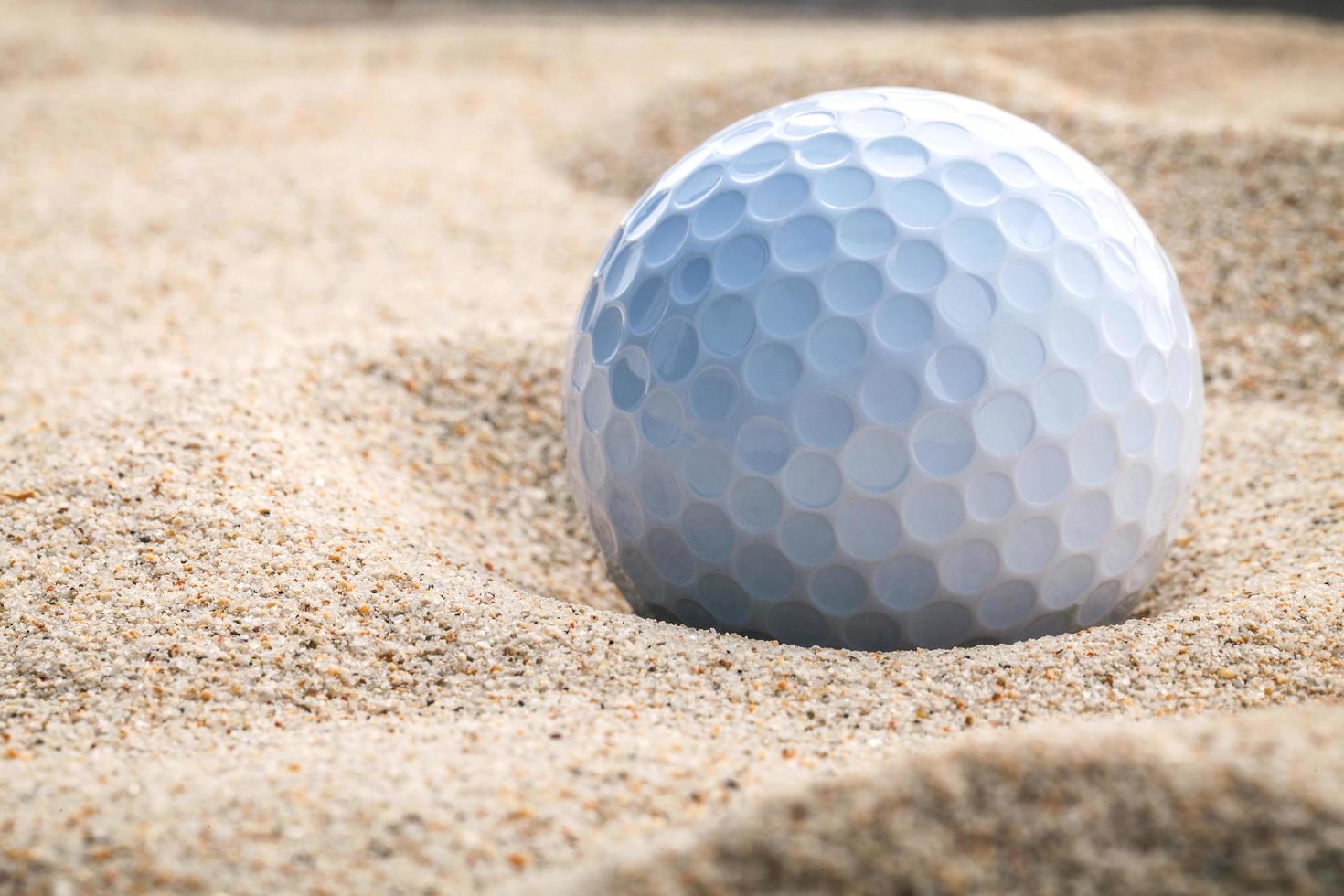 close-up van een golfbal in zand foto